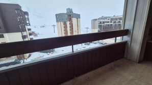 Ein Balkon mit Blick auf eine verschneite Straße und Gebäude.