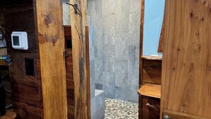 Ein Holzinnenraum mit einer gefliesten Duschkabine und einer kleinen Holzablage.
