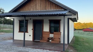 Ein modernes Einfamilienhaus mit überdachter Veranda, Eingangstür und kleiner Sitzgelegenheit im Freien.