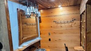 Ein rustikales Badezimmer mit Holzwänden, einem Holzwaschtisch, einem großen Spiegel und einem Holzstuhl.