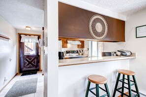 A modern kitchen with a central island, bar stools, and a decorative wall piece. - Comfortable 2-bedroom condo in Breckenridge for your getaway (Breckenridge)