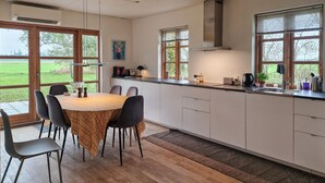 A modern kitchen with a dining area, featuring a wooden table, chairs, and a view of the outdoors. - 3 bedroom cozy home in Vrå (Vrå)