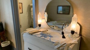 Une commode blanche avec des tiroirs, un miroir et deux lampes allumées.