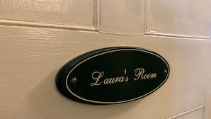 Une pancarte sur une porte indique : « Chambre de Laura ».