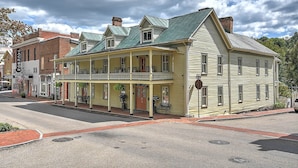 A historic building with a balcony and a porch, featuring a brick facade and a green roof. - The Tub Room at The Historic Eureka Inn and Event Center (Jonesborough)