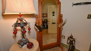 A room with a mirror, a lamp, a small table with a decorative item, and a coat rack with a coat. - Angeline's Room at The Historic Eureka Inn and Event Center (Jonesborough)