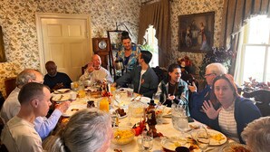 A dining room with a floral wallpaper, a clock, and a painting on the wall. - The Maxwell Room at The Historic Eureka Inn (Jonesborough)
