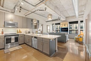 A modern kitchen with stainless steel appliances, a large island, and pendant lighting. - Sable 205 - Two Bedroom (Minneapolis)
