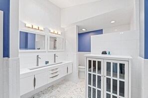 Un bagno moderno con piastrelle bianche e blu, un mobile lavabo doppio e un armadietto in vetro.