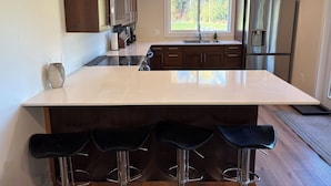 A modern kitchen with a large island, stainless steel appliances, and dark wooden cabinets.