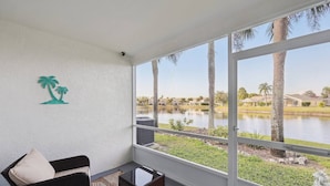 A balcony with a view of a lake, palm trees, and a building complex. - Peaceful Lakeside Stay with Private Screened Patio-Community Pool-Near Beaches (Bradenton)