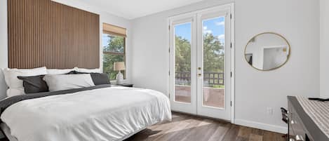 A bedroom with a bed, a ceiling fan, a window with blinds, and a view of the outdoors.