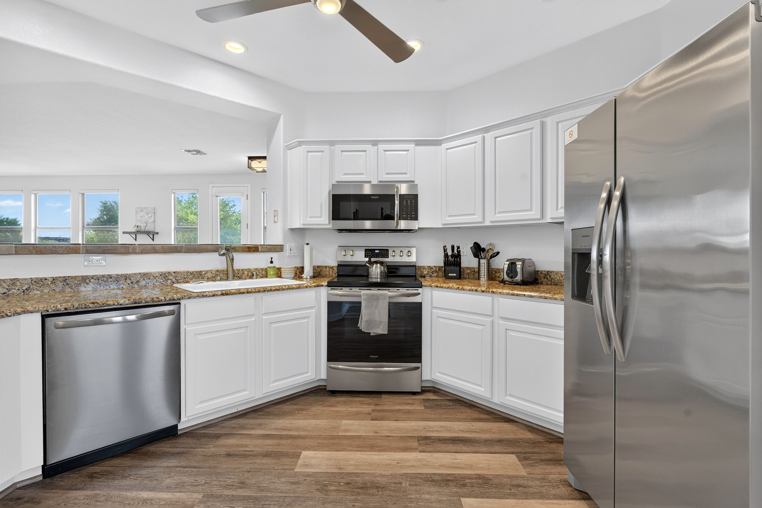 A modern kitchen with white cabinets, stainless steel appliances, and a granite countertop.