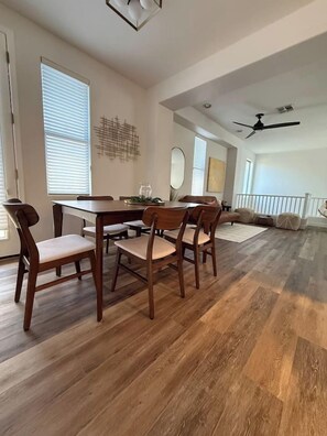 A dining area with a wooden table and chairs, a ceiling fan, and a view of the living room. - Kierland Retreat | Golf Views + Pool (Scottsdale)