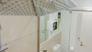 A modern bathroom with a glass shower enclosure, a white sink, and a toilet. - Serene Studio Apartment at Oasis Park (Accra)