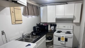 Una cucina compatta con lavatrice, fornello e microonde.