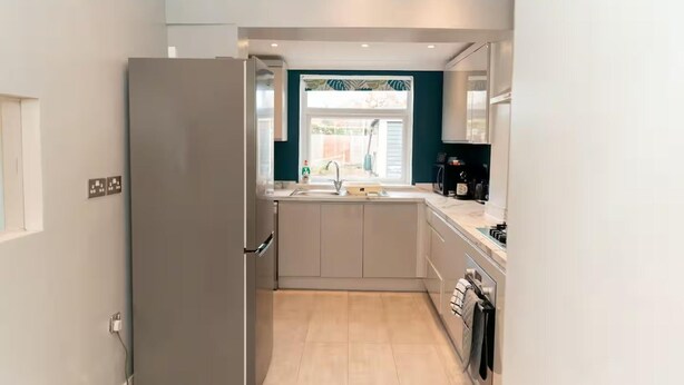 Una cocina moderna con refrigerador empotrado, un lavamanos y un ventanal con vistas al exterior.