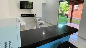 A modern kitchen with a black countertop, a TV mounted on the wall, and a sliding glass door leading to an outdoor area.