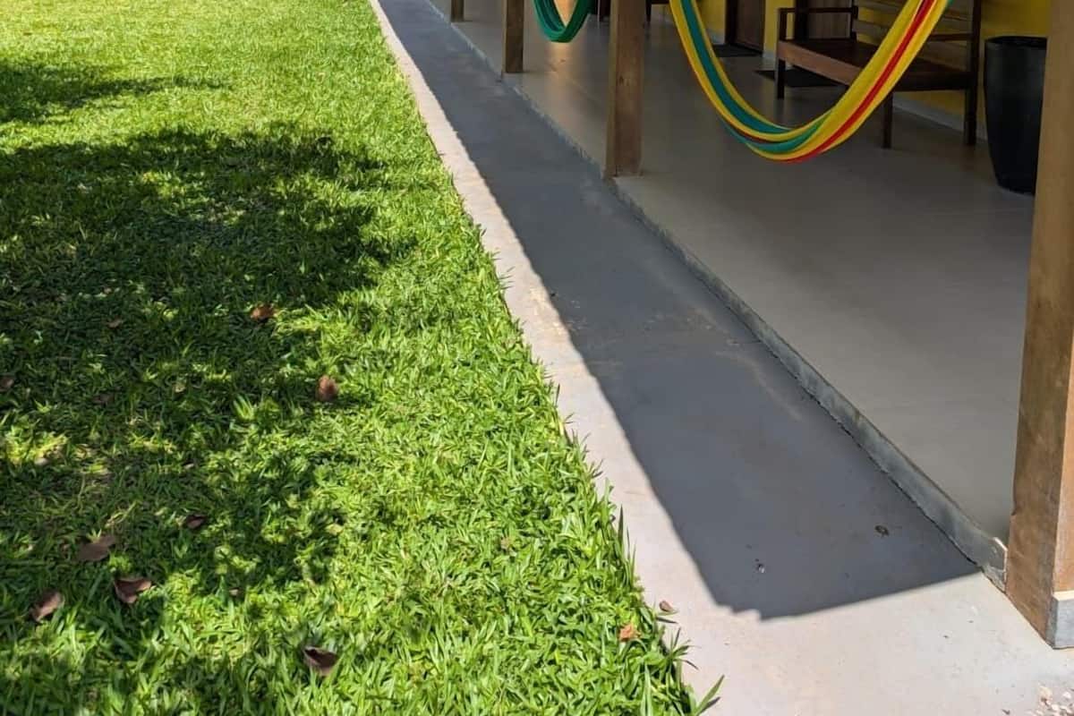 A covered outdoor area with a grassy lawn, hammocks, and yellow walls.