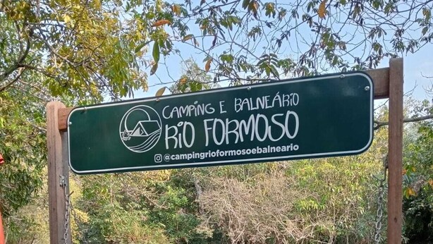 A wooden swing bridge over a river with a sign for Rio Formoso.