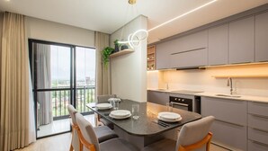 A modern kitchen with grey cabinets, a built-in oven, and a dining area with a table set for four. - Fully Equipped Apartments in a Building With a Pool, 400m From Picarras Beach - Bacs (Picarras)