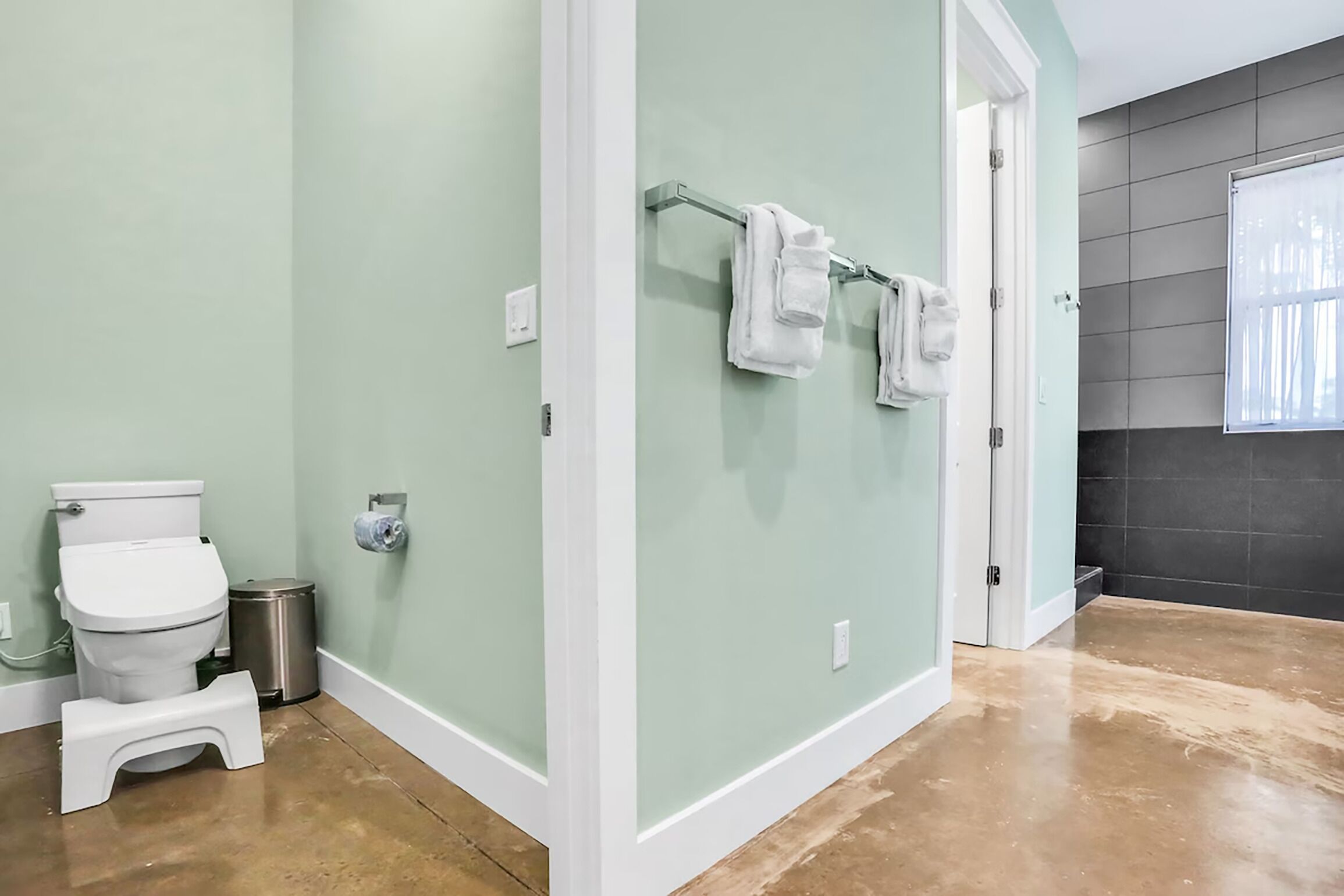 Une salle de bain équipée de toilettes, d’une poubelle et d’un porte-serviettes.