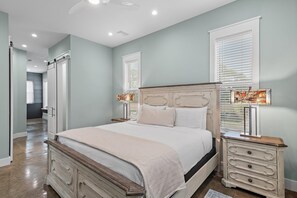 A bedroom with a large bed, bedside tables, and a nightstand with a lamp. - Down da Road (Miramar Beach)