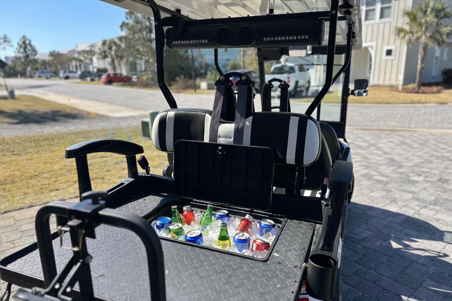 A golf cart with a tray table holding several cans of soda.