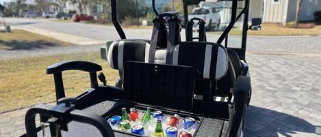 A golf cart with a tray table holding several cans of soda.