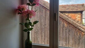 Ein Holztisch mit einer Vase voller rosa Blumen und einer schwarzen Tasse.