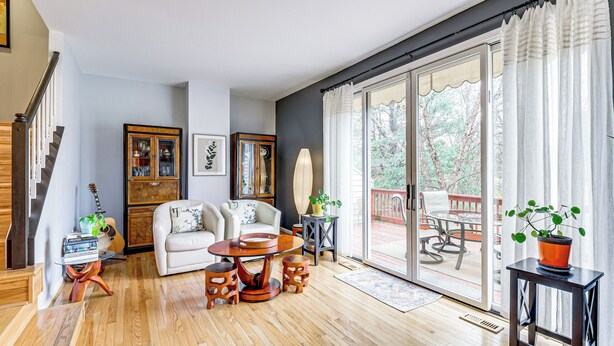Un salón amplio con piso de madera, un sofá blanco, una mesa de centro redonda y un comedor con mesa y sillas.