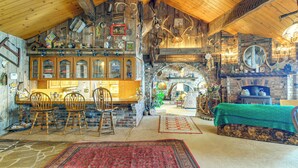 Un intérieur rustique avec des poutres apparentes, une cheminée en briques et un coin repas doté de chaises en bois.