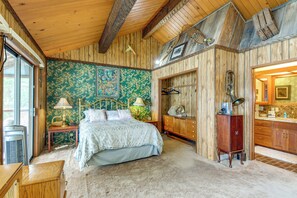 Ein Schlafzimmer mit Bett, Nachttisch, Kommode und einem großen Fenster.