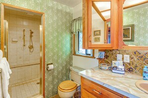 Ein Badezimmer mit Dusche, Toilette, Waschtisch und Spiegel.