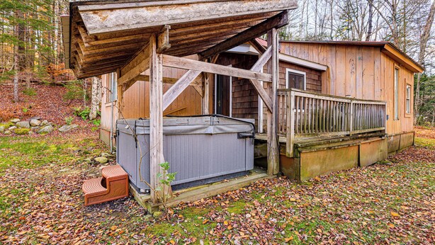 Een rustieke houten blokhut met een hottub, een houten terras en een omheind gebied.