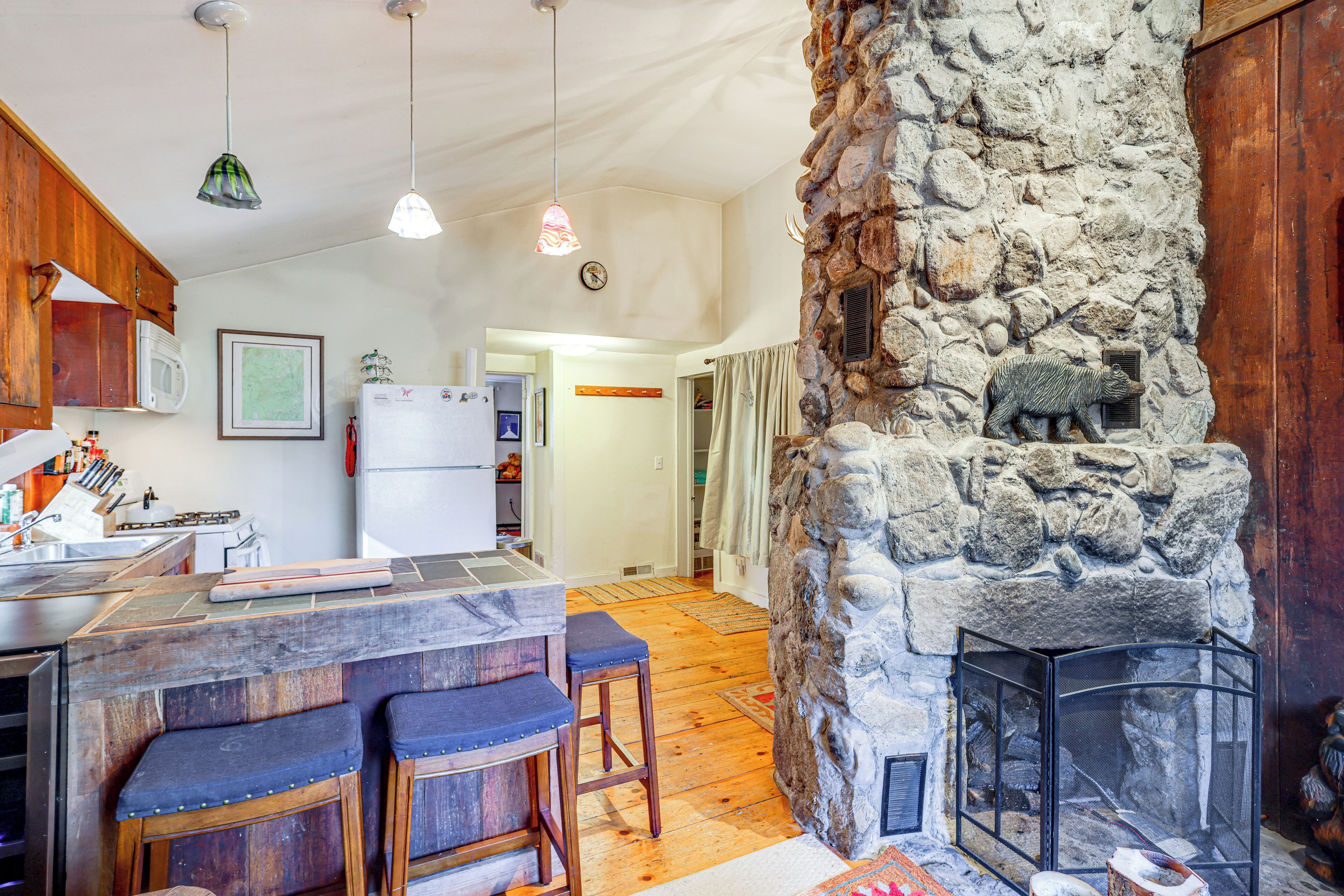 A kitchen with wooden cabinets, a refrigerator, and a stone wall with a bear sculpture.