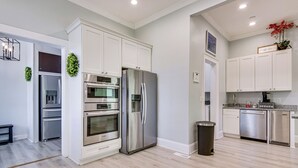 Una cocina moderna con electrodomésticos de acero inoxidable, armarios blancos y piso de madera clara.