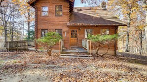 A log cabin with a wooden porch, a front door, and a small staircase leading up to the entrance. - On-Site Trails, Pond! Rustic Harpers Ferry Cabin (Harpers Ferry)