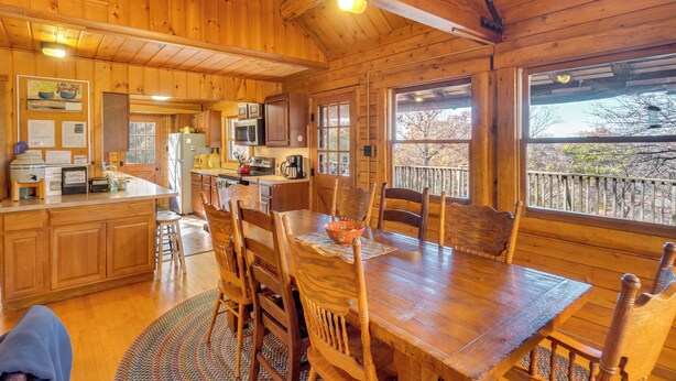 A wooden cabin interior with a kitchen, dining area, and large windows. - On-Site Trails, Pond! Rustic Harpers Ferry Cabin (Harpers Ferry)