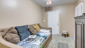 A small, well-lit room with a sofa, a small stool, a door, and an exit sign. - Great for Gatherings! Rural Fort Valley Retreat   (Fort Valley)