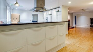 A modern kitchen with white cabinetry, a central island, pendant lighting, and a wooden floor. - Serene & Spacious! Family-Friendly Catharpin Home (Catharpin)