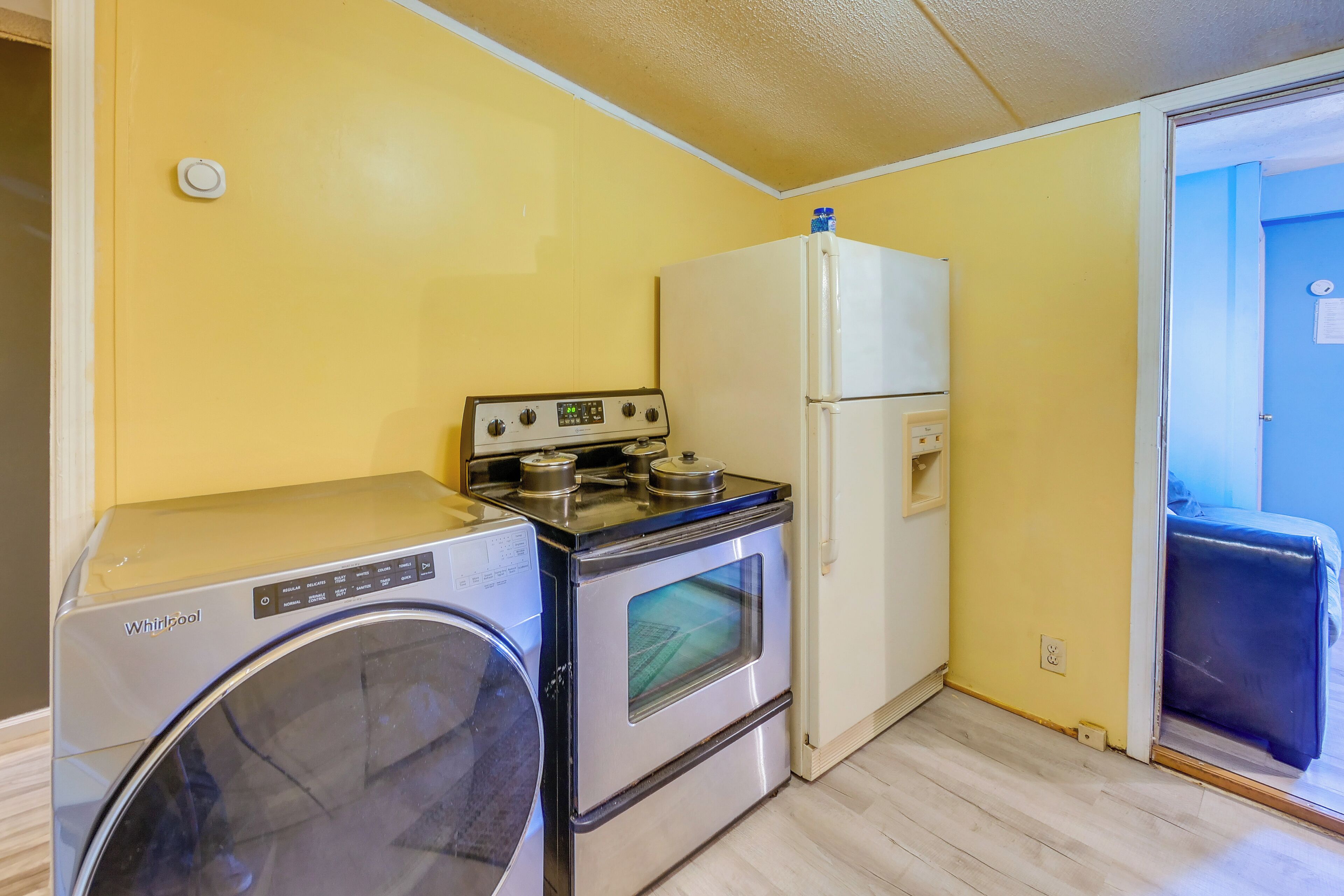 A compact kitchen with a Whirlpool washer, an oven, and a refrigerator.