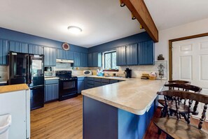 A kitchen with blue cabinets, a central island, a refrigerator, a stove, and a microwave. - 5BR Poconos Cabin Near Jim Thorpe, Sleeps 10 (Jim Thorpe)