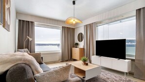 Ein modernes Hotelzimmer mit einer Couch, einem Couchtisch, einem Fernseher und großen Fenstern mit Meerblick.