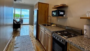 Una cocina moderna con armarios de madera, encimeras de granito, microondas integrado y cocina a gas.