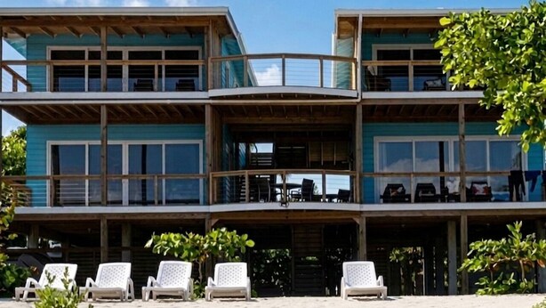 Un immeuble à plusieurs étages doté de balcons, d’un espace extérieur aménagé pour s’asseoir et offrant une vue sur la plage.