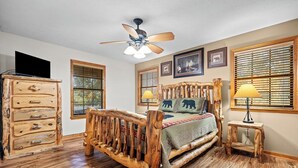 A bedroom with a wooden bed, a ceiling fan, a dresser, and two windows with blinds. - Wears Valley 3BR Retreat - Hot Tub, Multicade, Pool Table & Hoops! (Sevierville)