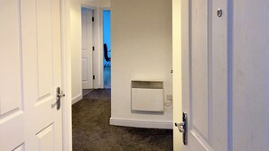 Un pasillo con puertas blancas, un radiador y una lámpara en el techo.