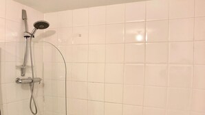 Un baño moderno con ducha de vidrio, una bañera blanca y un inodoro.