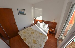 A bedroom with a bed, a nightstand, a wooden headboard, a framed picture on the wall, and a sliding glass door leading to a balcony. - Stunning apartment in Turanj with house sea view (Turanj)